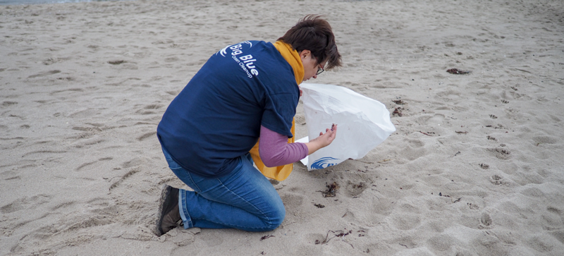 Une femme sur la plage avec un sac poubelle