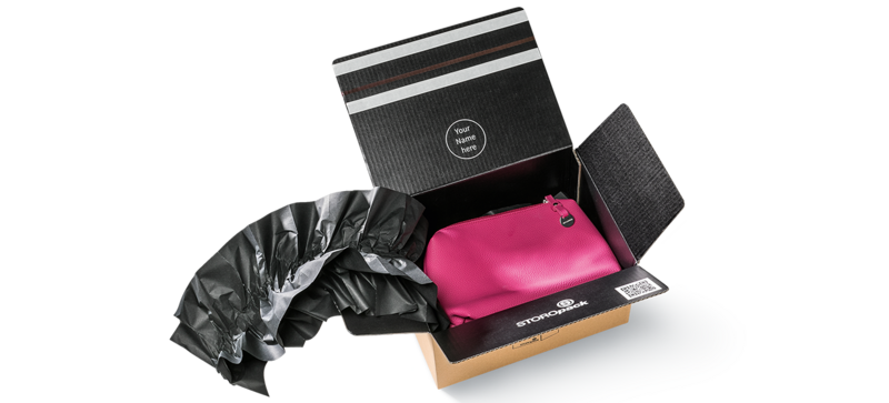 Un carton contenant un sac rose et des coussins d’air noirs