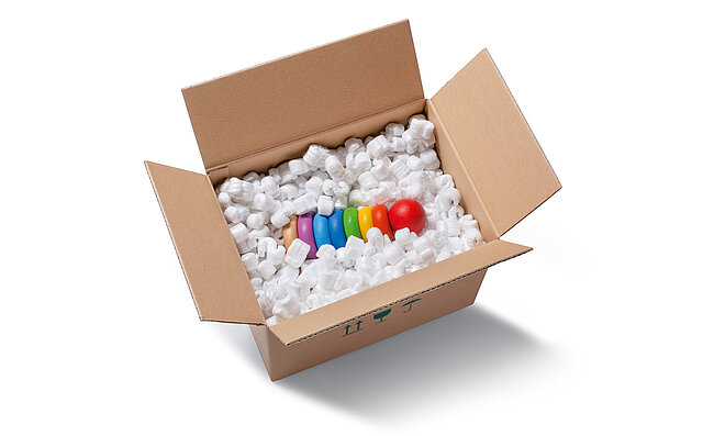 Un carton contenant un jouet pour enfant  et des chips d’emballage blanches en forme de S