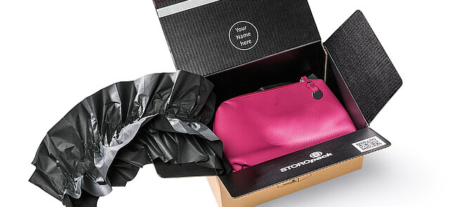 Un carton contenant un sac rose et des coussins d’air noirs