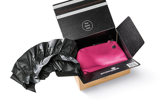 Un carton contenant un sac rose et des coussins d’air noirs