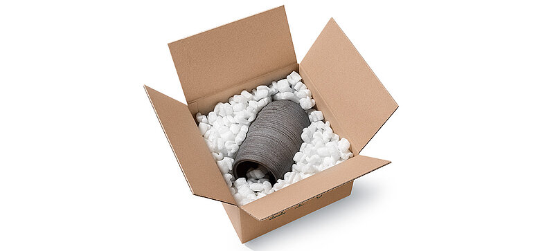 Un carton contenant de vase en porcelaine et des chips d’emballage en bioplastique en forme de S