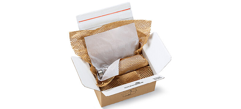 A box containing a bottle and other items wrapped in brown and white paper padding.