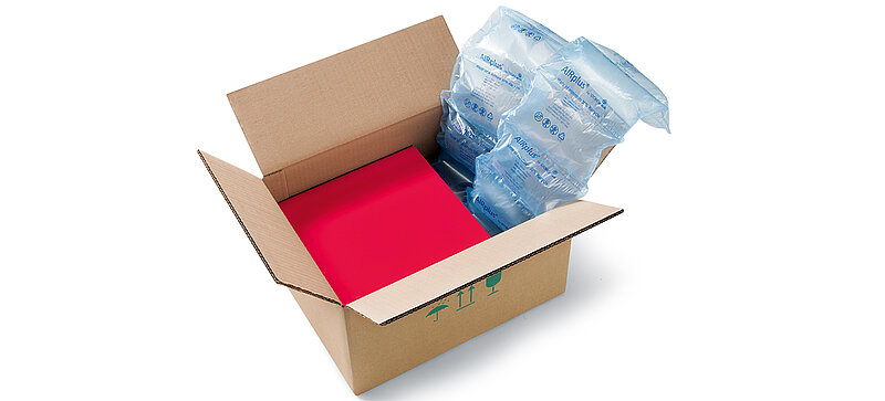Un carton contenant une boîte rouge et des coussins d’air 100% RECYCLED 